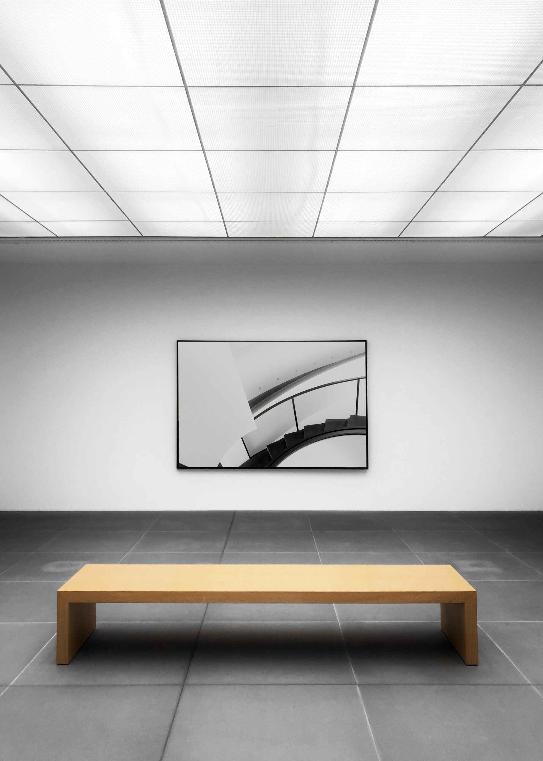 A photo frame showing stair case in a white wall & having a desk in front of it